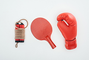 top view of jumping rope near ping pong racket and red boxing glove isolated on white