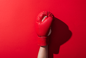 cropped view of woman in leather boxing glove on red