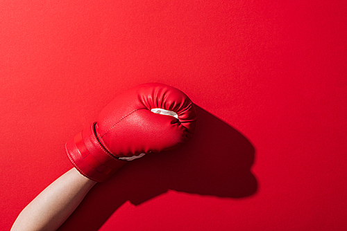 cropped view of woman in boxing glove on red