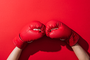 cropped view of woman in pair of boxing gloves on red