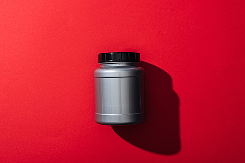 top view of grey plastic jar with protein on red