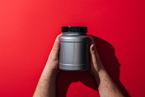 cropped view of man holding grey jar in hands on red