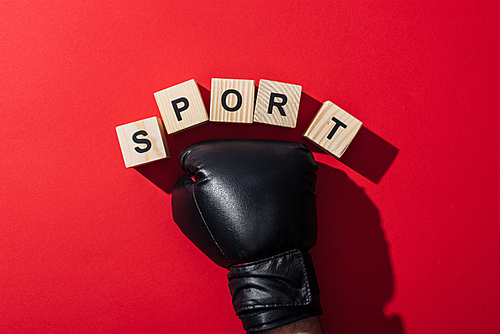 cropped view of man in boxing glove near wooden cubes with sport lettering on red