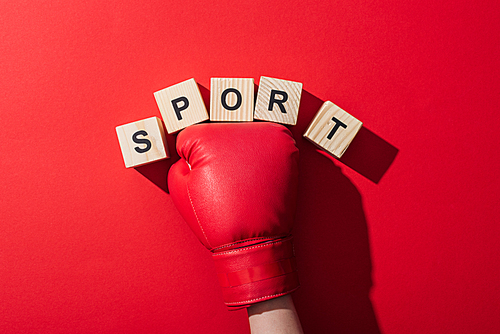 cropped view of woman in boxing glove near wooden cubes with sport lettering on red