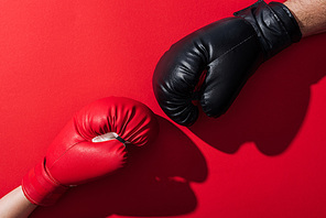 cropped view of man and woman in leather boxing gloves on red
