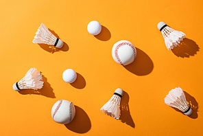 top view of shuttlecocks with feathers near softballs and golf balls on yellow