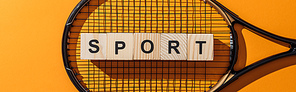 panoramic shot of wooden cubes with sport lettering near tennis racket on yellow