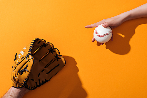 cropped view of man in brown baseball glove near woman holding softball on yellow