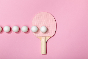 flat lay with white ping-pong balls and racket on pink background