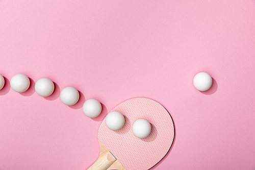 flat lay with white plastic table tennis balls and racket on pink background