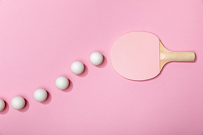 top view of table tennis balls and pink racket on pink background