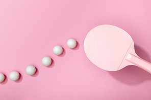 top view of white table tennis balls and racket on pink background
