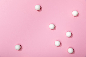 top view of white table tennis balls scattered on pink background