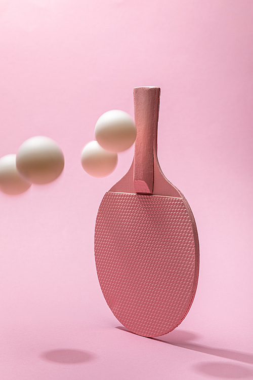 ping-pong racket and white balls on pink background with copy space