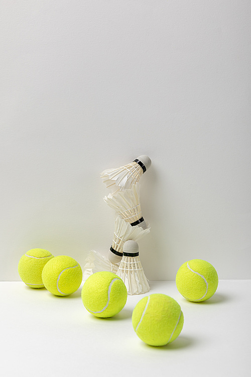 white badminton shuttlecocks and yellow tennis balls on white background