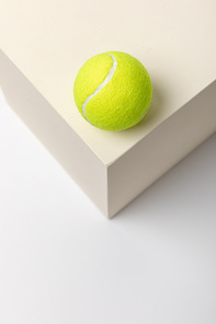 bright yellow tennis ball on cube on white background