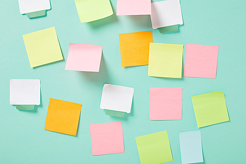multicolored empty sticky notes with copy space on turquoise wall