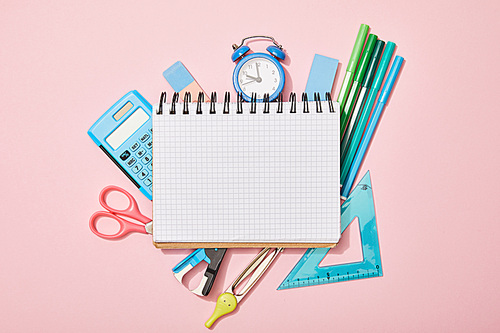top view of school supplies near blank notebook isolated on pink