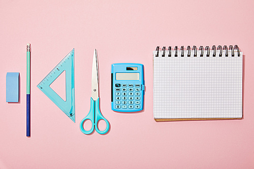 flat lay with blue school supplies near blank notebook isolated on pink