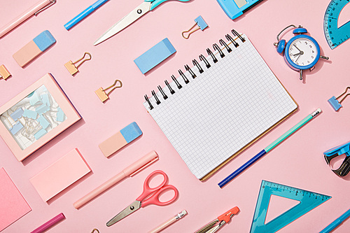 flat lay with blue and pink school supplies and blank notebook isolated on pink