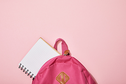 top view of blank notebook near backpack isolated on pink