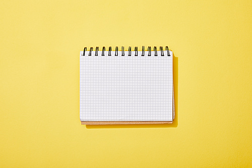 top view of blank white notebook on yellow background
