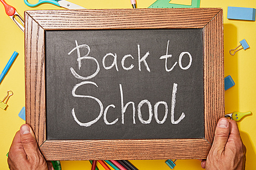 cropped view of man holding chalkboard with back to school lettering