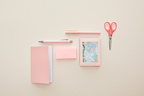 top view of pink stationery near box with paper clips isolated on beige