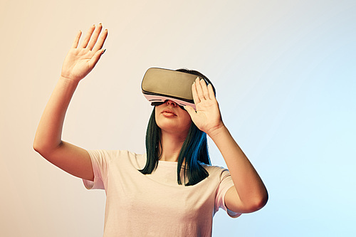 young woman wearing virtual reality headset  and gesturing on beige and blue