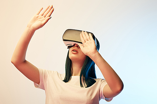 brunette young woman wearing virtual reality headset  and gesturing on beige and blue