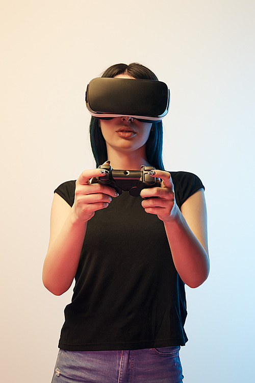 KYIV, UKRAINE - APRIL 5, 2019: Brunette woman playing video game while wearing virtual reality headset on beige and blue