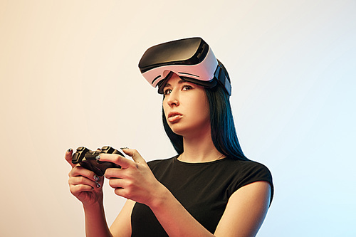 KYIV, UKRAINE - APRIL 5, 2019: Beautiful brunette woman playing video game while wearing virtual reality headset on beige and blue