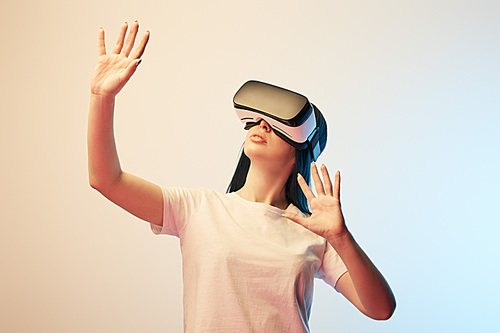 young woman in virtual reality headset gesturing on beige and blue