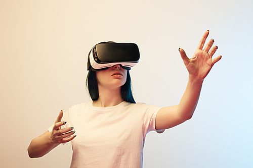 brunette girl in virtual reality headset gesturing on beige and blue