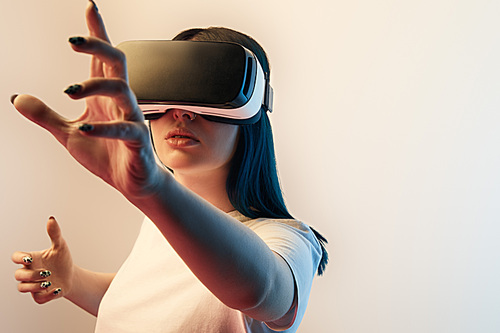 selective focus of woman in virtual reality headset gesturing on beige