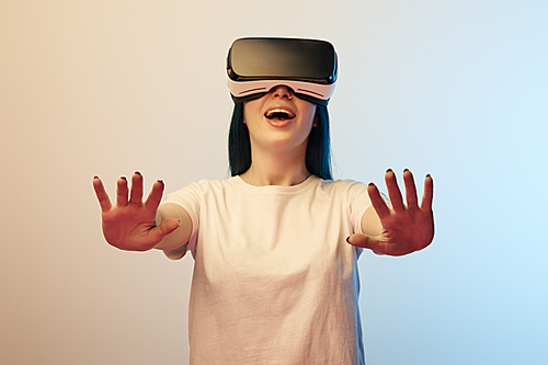 selective focus of cheerful woman in virtual reality headset gesturing on beige and blue