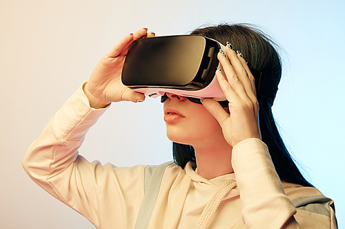 beautiful brunette woman touching virtual reality headset on beige and blue