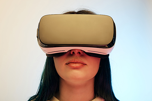 low angle view of brunette woman in virtual reality headset on beige and blue