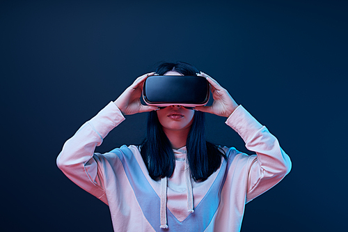 brunette young woman touching virtual reality headset on blue