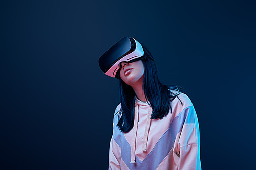 young brunette woman wearing virtual reality headset on blue