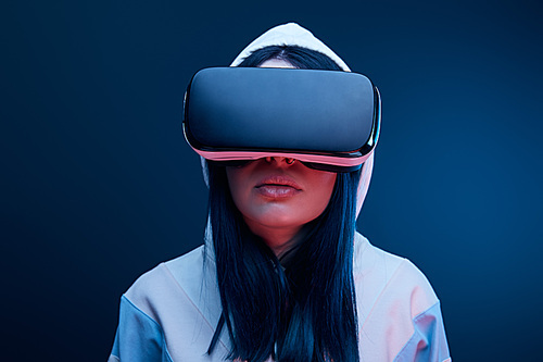 brunette girl in hood wearing virtual reality headset on blue