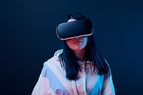 brunette young woman using virtual reality headset on blue
