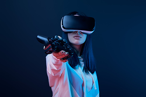 KYIV, UKRAINE - APRIL 5, 2019: Selective focus of young woman holding joystick while using virtual reality headset on blue