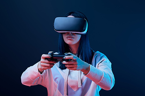 KYIV, UKRAINE - APRIL 5, 2019: Selective focus of young woman playing video game while wearing virtual reality headset on blue