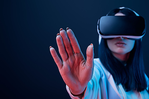 selective focus of hand of girl using virtual reality headset and gesturing on blue