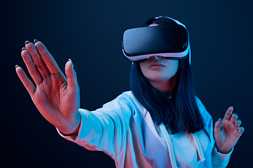 selective focus of girl gesturing while using virtual reality headset on blue