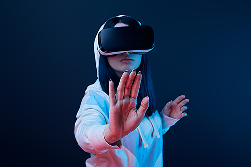 selective focus of woman gesturing while using virtual reality headset on blue