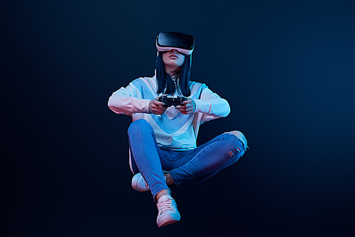 KYIV, UKRAINE - APRIL 5, 2019: Woman holding joystick while levitating, playing video game and wearing virtual reality headset on blue