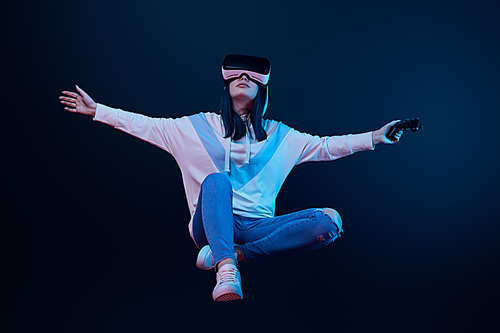 KYIV, UKRAINE - APRIL 5, 2019: Young woman in virtual reality headset levitating and holding joystick on blue