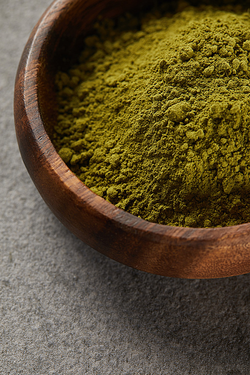 close up view of green matcha powder in wooden bowl